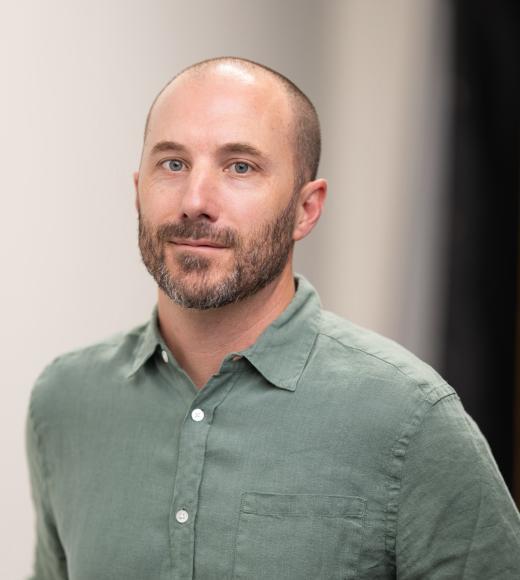 a photo of a man in a muted green shirt.