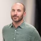 a photo of a man in a muted green shirt.